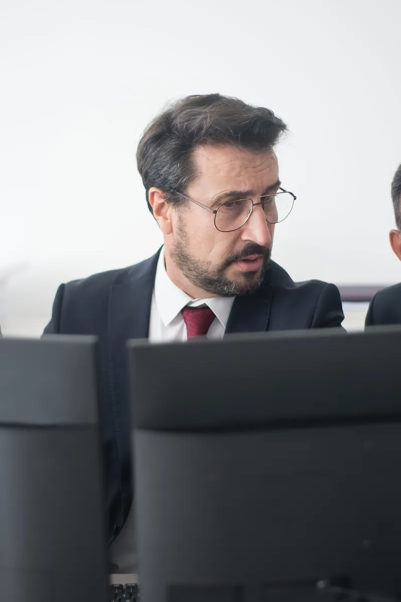 A man in a suit looking at a computer monitor